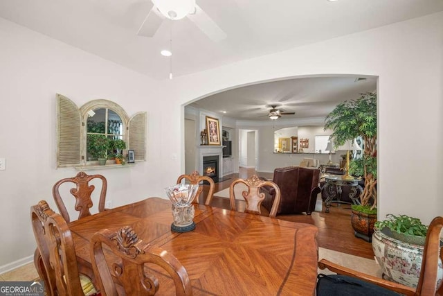 6408 Autumn Crest Ln, Hoschton, GA 30548 - dining space with a ceiling fan, a lit fireplace, arched walkways, recessed lighting, and baseboards
