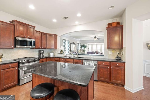 6408 Autumn Crest Ln, Hoschton, GA 30548 - kitchen with stainless steel appliances, a sink, a kitchen island, a breakfast bar, and light wood finished floors