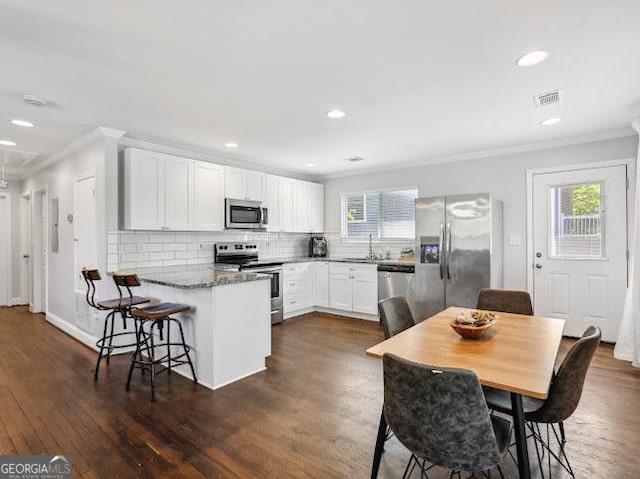 1599 Ezra Church Dr NW, Atlanta, GA 30314 - kitchen featuring crown molding, visible vents, a peninsula, a sink, and stainless steel appliances
