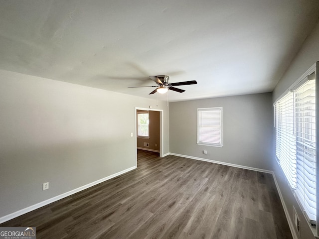empty room with ceiling fan, visible vents, baseboards, and dark wood-type flooring