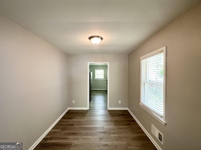 unfurnished room with baseboards, visible vents, and dark wood-style floors
