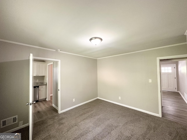unfurnished bedroom featuring visible vents, baseboards, crown molding, and dark colored carpet