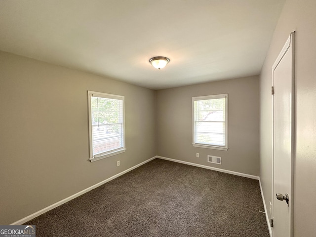 unfurnished bedroom featuring visible vents, baseboards, and dark colored carpet