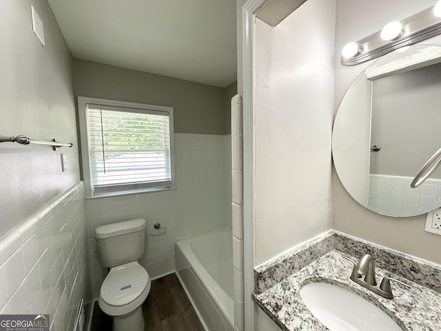 full bath featuring vanity, toilet, a bathtub, tile walls, and wood finished floors