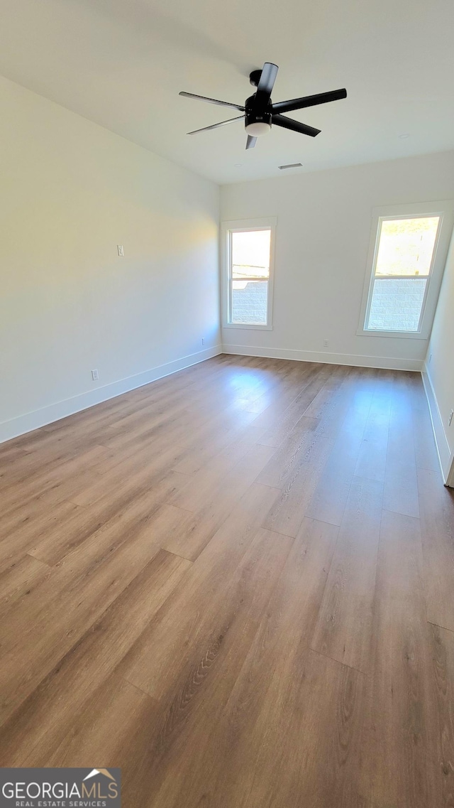 unfurnished room with baseboards, ceiling fan, and light wood-style flooring
