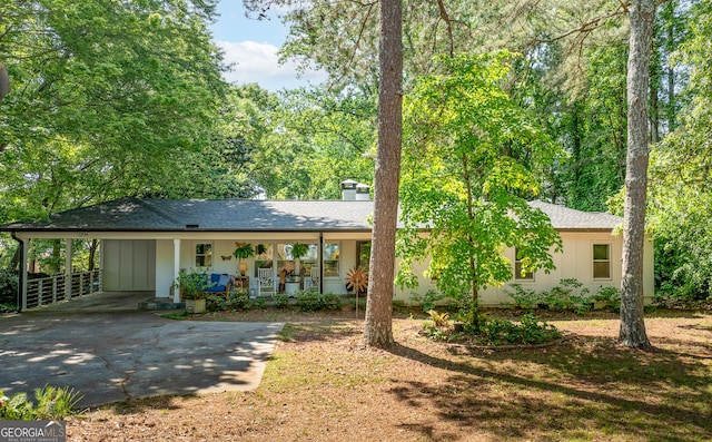 ranch-style house with a porch, board and batten siding, driveway, and a carport