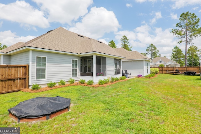 back of house featuring a fenced backyard, a sunroom, a yard, and roof with shingles