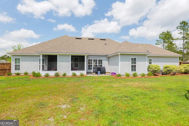 back of house with roof with shingles, fence, a lawn, and a patio area