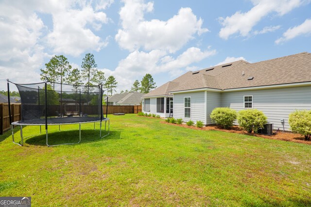 view of yard featuring a fenced backyard, a trampoline, and central AC unit
