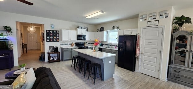 77 Willowrun Dr SW, Rome, GA 30165 - kitchen with a kitchen breakfast bar, ceiling fan, light countertops, a sink, and black appliances