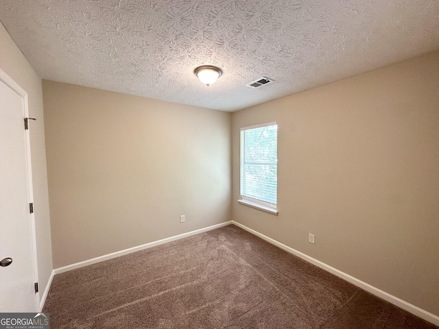 unfurnished room featuring carpet floors, a textured ceiling, baseboards, and visible vents