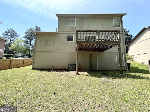rear view of house with a lawn, fence, a wooden deck, and cooling unit