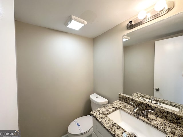 half bath featuring vanity and toilet
