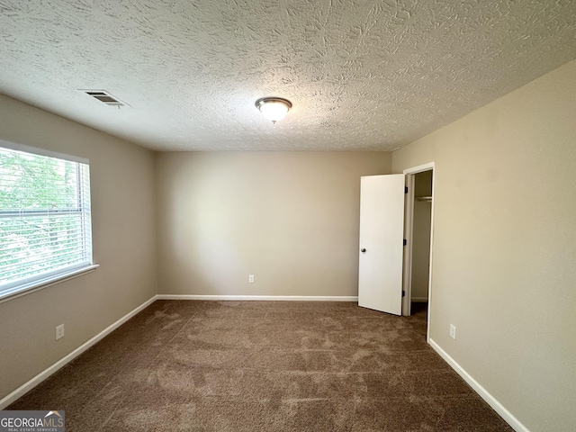 empty room featuring visible vents, a textured ceiling, baseboards, and carpet floors