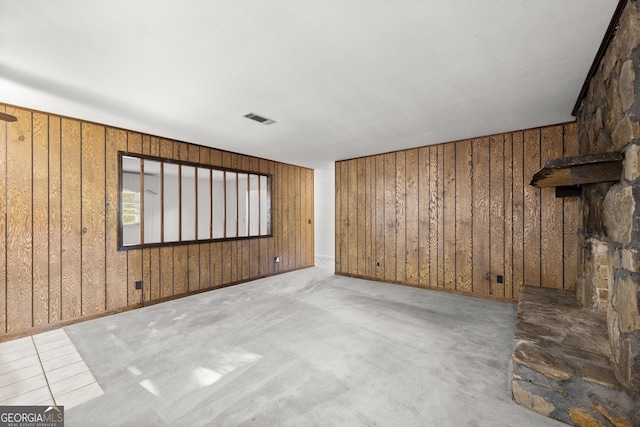 unfurnished living room featuring visible vents and wood walls