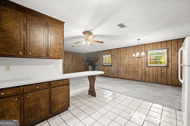kitchen with visible vents, freestanding refrigerator, wood walls, ceiling fan, and light countertops