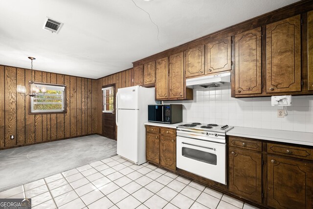 kitchen with visible vents, white appliances, wooden walls, light countertops, and under cabinet range hood
