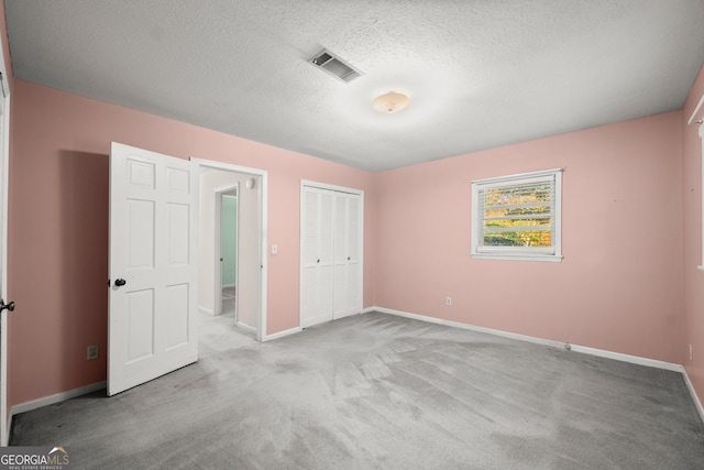 unfurnished bedroom featuring a textured ceiling, visible vents, baseboards, a closet, and carpet flooring