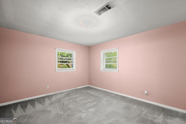 carpeted spare room featuring baseboards, a textured ceiling, and visible vents