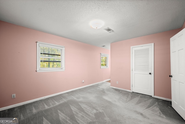 unfurnished bedroom featuring carpet floors, a textured ceiling, baseboards, visible vents, and a closet