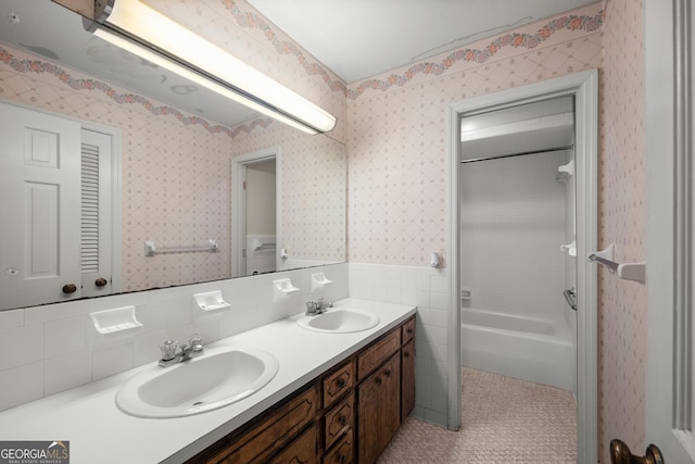 bathroom with double vanity, a sink, wallpapered walls, and tile walls