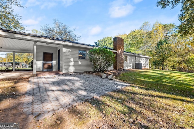 rear view of property featuring a lawn, a chimney, and cooling unit