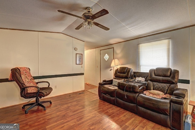 cinema room featuring crown molding, ceiling fan, a textured ceiling, wood finished floors, and lofted ceiling