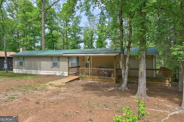 view of front of property featuring a porch, a chimney, and metal roof