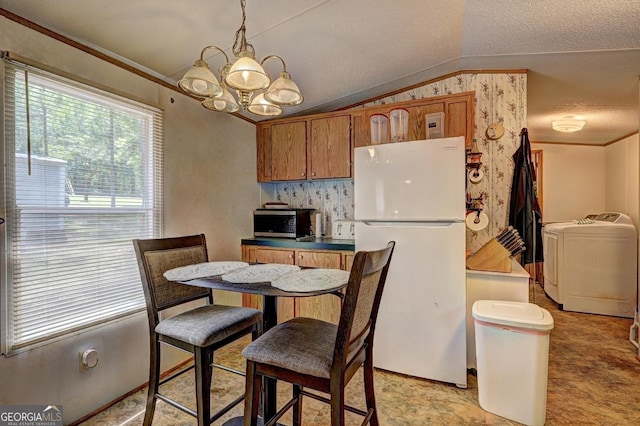 dining space with crown molding, a notable chandelier, vaulted ceiling, and washing machine and clothes dryer