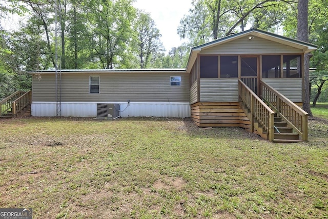 rear view of house featuring a sunroom, a lawn, central AC, and stairway