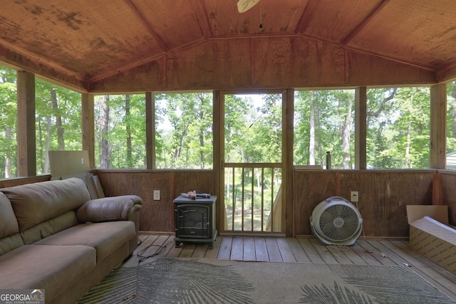 sunroom featuring an outdoor living space, a wood stove, vaulted ceiling, a wooden deck, and hardwood / wood-style floors