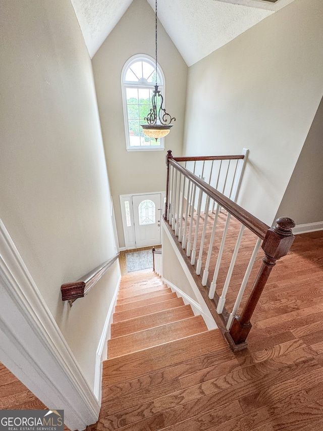 stairway with baseboards, plenty of natural light, and wood finished floors