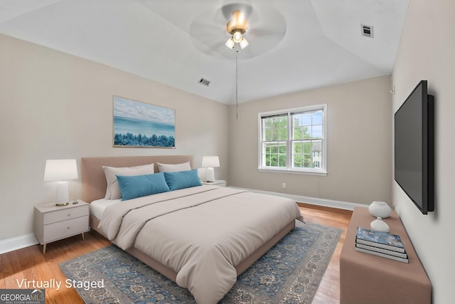 bedroom with baseboards, a ceiling fan, light wood-type flooring, and visible vents