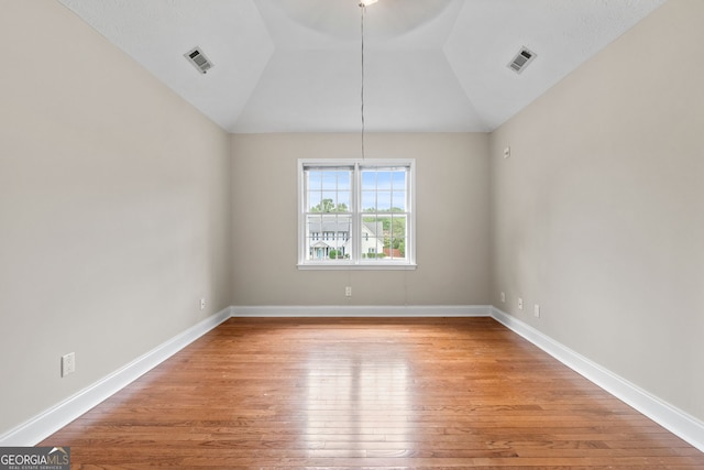 unfurnished dining area with light wood-style floors, baseboards, vaulted ceiling, and visible vents