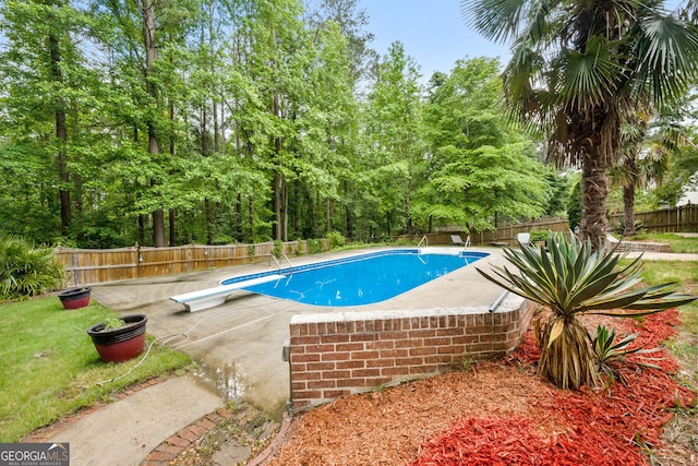 view of swimming pool with a fenced in pool, a diving board, a fenced backyard, and a patio area