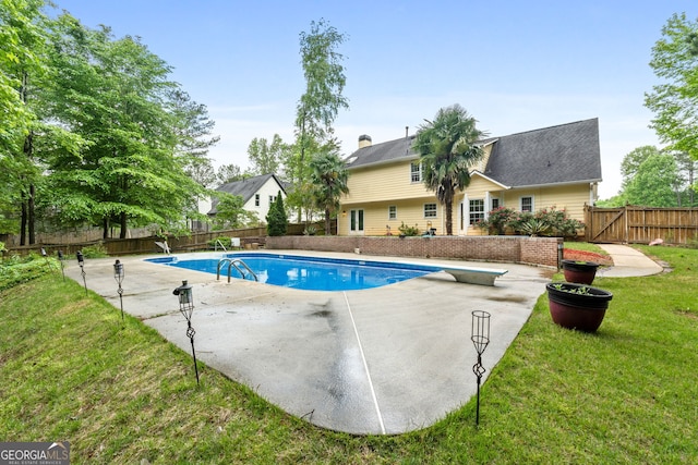 view of swimming pool featuring a fenced backyard, a diving board, a yard, and a patio area
