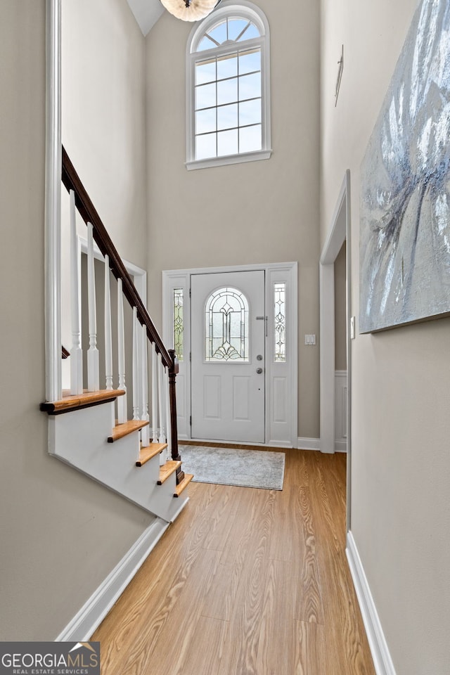 entryway with a healthy amount of sunlight, a high ceiling, stairs, and wood finished floors