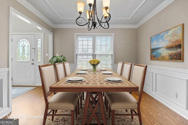 dining space featuring an inviting chandelier, wainscoting, and light wood-type flooring