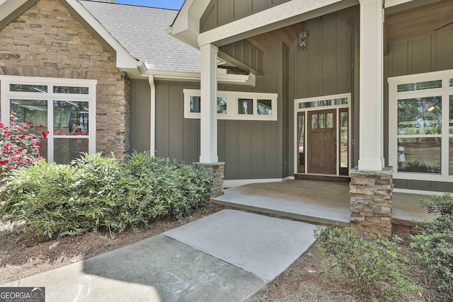 property entrance featuring roof with shingles, board and batten siding, and stone siding