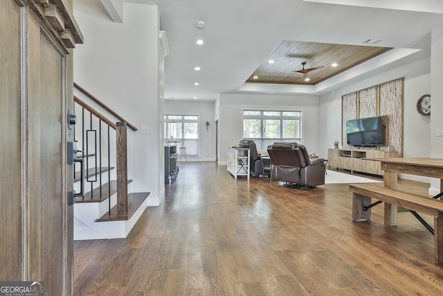 living area featuring wood finished floors, stairway, recessed lighting, a raised ceiling, and a ceiling fan