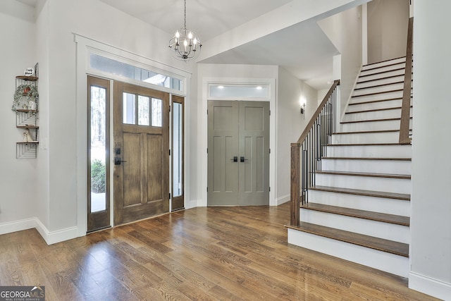 foyer with stairway, baseboards, wood finished floors, and a chandelier
