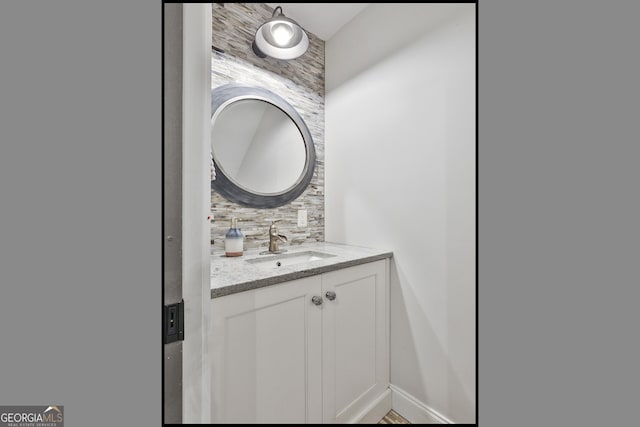 bathroom with baseboards, decorative backsplash, and vanity