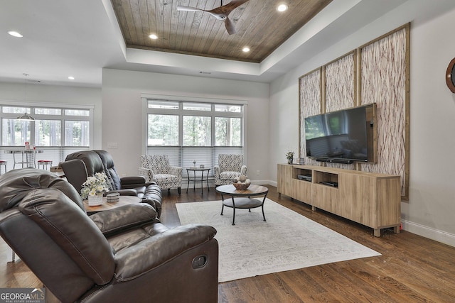 living room featuring baseboards, dark wood-style flooring, a tray ceiling, and ceiling fan