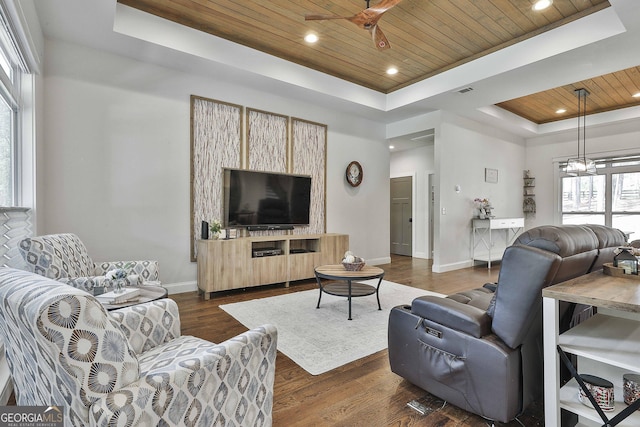 living room with ceiling fan, a raised ceiling, baseboards, wooden ceiling, and dark wood-type flooring