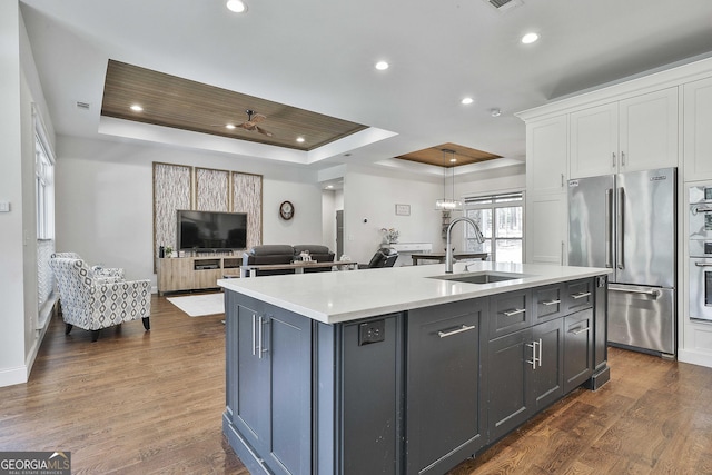 kitchen featuring high end fridge, light countertops, a raised ceiling, white cabinetry, and a sink