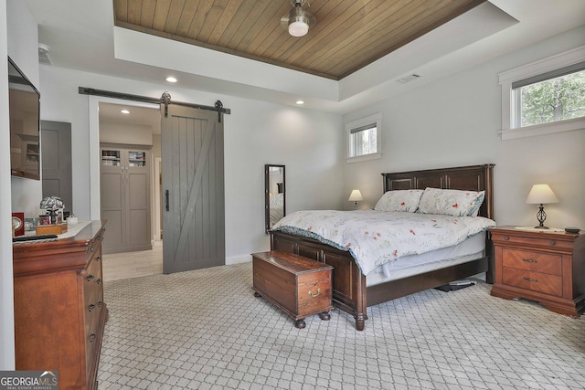 bedroom featuring visible vents, a barn door, a tray ceiling, and multiple windows