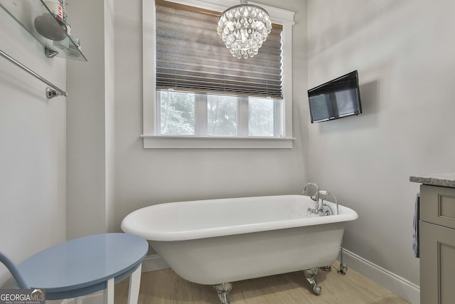bathroom featuring baseboards, vanity, a freestanding bath, and an inviting chandelier