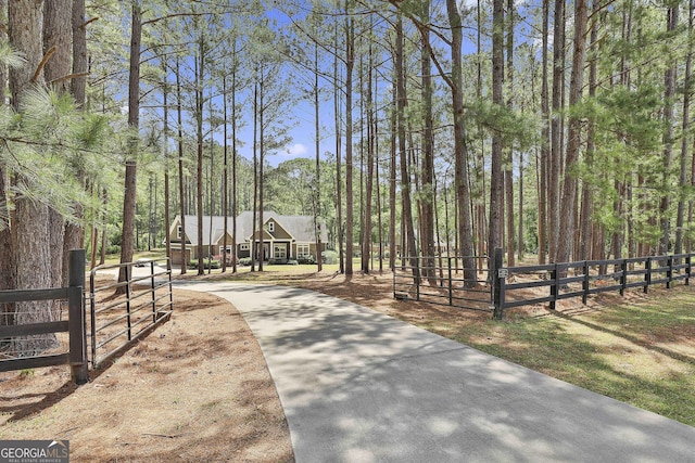 view of home's community featuring a forest view, fence, and a gate