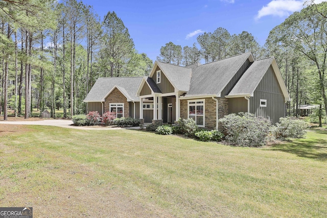 craftsman-style house featuring a shingled roof, board and batten siding, stone siding, and a front yard