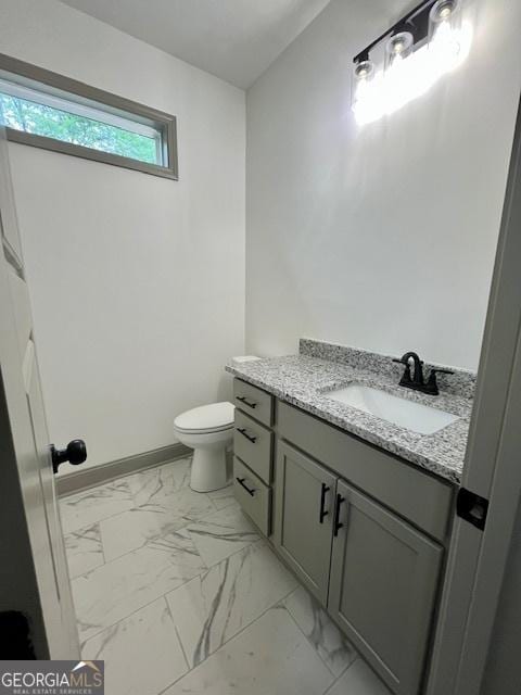 bathroom with vanity, baseboards, toilet, and marble finish floor